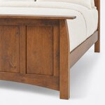 Footboard close-up of a Craftsman panel bed, showing the overhanging cap rail, a flared corner post and a square leg.