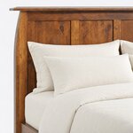 Headboard close-up of a Craftsman panel bed, showing recessed flat panels, a flared post and the overhanging cap rail.