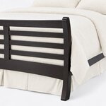 Footboard close-up of a contemporary sleigh bed, showing a curved corner post, horizontal slats and an arched bottom rail.