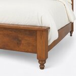 Footboard close-up of a traditional post bed, showing the overhanging cap rail, a square corner post and a turned foot.