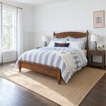Diagonal angled room view showing the left side of a traditional post bed with a low footboard, in a wainscoted bedroom.