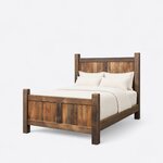 Diagonal angled view showing the left side of a farmhouse panel bed, with planked two-panel ends and chunky square posts.