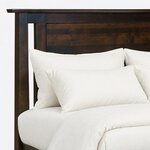 Headboard close-up of a transitional panel bed, showing the overhanging cap rail, a planked inset panel and a slim cutout.
