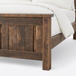 Footboard close-up of a farmhouse panel bed, showing the overhanging cap, framed plank infill and a square corner leg.