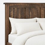 Headboard close-up of a farmhouse panel bed, showing vertical plank infill under a broad top rail and a thin cap rail.