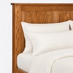 Headboard close-up of a Shaker panel bed, showing the overhanging cap rail, a broad top rail and a recessed flat panel.