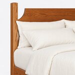 Headboard close-up of a Shaker panel bed, showing a scooped panel shoulder beside a tall square post with a chamfered top.