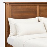 Headboard close-up of a platform storage bed, showing framed flat panels, a pegged square post and the overhanging cap rail.