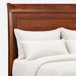 Headboard close-up of a classic sleigh bed, showing the rolled top rail, a curved side post and a large recessed flat panel.