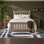 Front room view of a rustic slat bed with a capped slatted footboard, in an olive-green bedroom with a picture ledge.