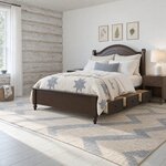 Diagonal angled room view showing the left side of a traditional storage bed with side drawers, in a log-walled bedroom.
