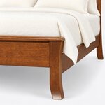 Footboard close-up of a Shaker panel bed, showing the rounded overhanging cap, a flared saber leg and a plain footboard.