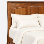 Headboard close-up of a Shaker panel bed, showing arch-topped raised panels, a gently curved post and a rounded top cap.