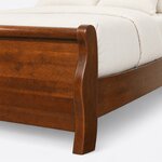 Footboard close-up of a traditional sleigh bed, showing the rolled top rail, an S-curved scroll post and a flared foot.