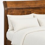 Headboard close-up of a transitional panel bed, showing the rear-curving post, a broad top panel and arched lower panels.