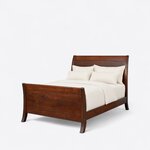 Diagonal angled view showing the left side of a modern sleigh bed, with a high panel footboard and outward-flared legs.
