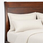 Headboard close-up of a modern sleigh bed, showing the swept-back post, a flat top rail and a broad solid panel.