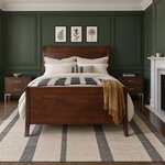 Front room view of a modern sleigh bed with a high panel footboard, in a green-paneled bedroom with a marble fireplace.