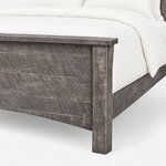 Footboard close-up of a rustic panel bed, showing a corbel bracket under the cap rail, planked infill and a square leg.