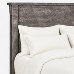 Headboard close-up of a rustic panel bed, showing horizontal planks, a corbel bracket and an overhanging cap rail.