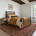 Diagonal angled room view showing the right side of a rustic log bed with a spindle footboard, in a white coffered bedroom.