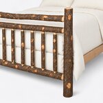 Footboard close-up of a rustic log bed, showing a round log post, a double top rail, round spindles and a plank side rail.