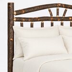 Headboard close-up of a rustic log bed, showing the arched crest rail, fan-set branch spokes and tapered spindle ends.