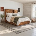 Diagonal angled room view showing the right side of a rustic bookcase bed with a low footboard, in a log cabin bedroom.