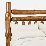 Headboard close-up of a rustic log bed, showing a thick log post, two stacked log rails and pointed flat slat tops below.