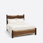 Diagonal angled view showing the right side of a live edge panel bed, with a crested headboard and a low slab footboard.