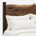 Headboard close-up of a live edge panel bed, showing the crested live edge top, a slab seam and a plain square post.