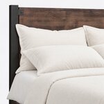 Headboard close-up of an industrial panel bed, showing the flat headboard panel, a square metal post and a bolted tab.
