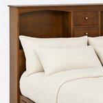 Headboard close-up of a bookcase storage bed, showing an arched open cubby, two center drawers with knobs and the flat cap.