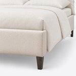 Footboard close-up of a contemporary upholstered bed, showing the low upholstered corner over a tapered square leg.
