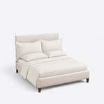 High angled view of a contemporary upholstered bed, looking down on the plain headboard, nailhead trim and low footboard.