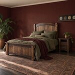 Diagonal angled room view showing the left side of a Mission panel bed with a capped plank footboard, in a burgundy bedroom.