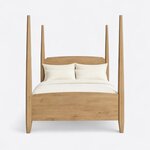 Front view of a classic pencil post bed, showing a crowned headboard with notched shoulders and an arched solid footboard.