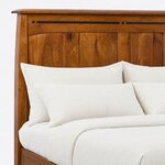 Headboard close-up of a Mission storage bed, showing an overhanging cap, an inlaid arched top rail and vertical plank panels.