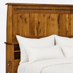 Headboard close-up of a Mission bookcase bed, showing the overhanging cap, an inlaid top rail, plank panels and a cubby.