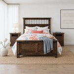Front room view of an industrial panel bed with a twisted metal grid headboard, in a white bedroom with sheer curtains.