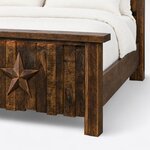 Footboard close-up of a rustic panel bed, showing the thick cap, a square block post, staggered planks and an applied star.