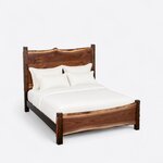 High angled view of a live edge panel bed, looking down on the wavy headboard crest, the side rails and the low footboard.