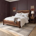 Diagonal angled room view showing the left side of a live edge panel bed with a low footboard, in a plum-paneled bedroom.