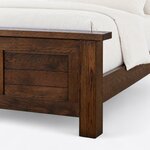 Footboard close-up of a rustic panel bed, showing the overhanging square-ended cap, a plank panel and a square block leg.