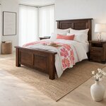 Diagonal angled room view showing the left side of a rustic panel bed with a capped headboard, in a bright white bedroom.