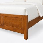 Footboard close-up of a modern panel bed, showing a square corner post and leg, a recessed panel and a flush top rail.