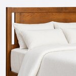 Headboard close-up of a modern panel bed, showing a flat inset panel, an open side slot, a square post and the top rail.