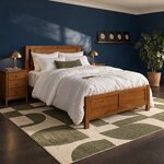 Diagonal angled room view showing the right side of a modern panel bed with a two-panel footboard, in a navy bedroom.