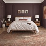 Front room view of a contemporary platform bed with a solid panel headboard, in a plum-paneled bedroom with crown molding.