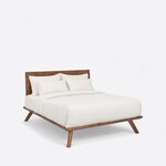 Diagonal angled view showing the right side of a contemporary platform bed, with a solid panel headboard and splayed legs.